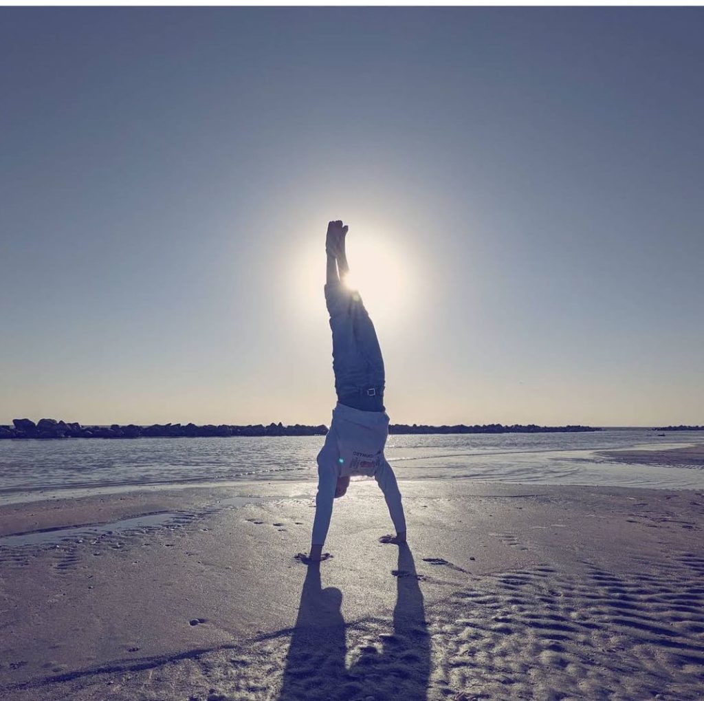 person does handstand alone on the beach